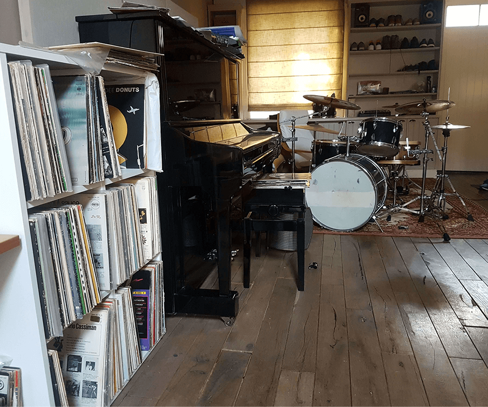 Record case with piano next to it and drumkit